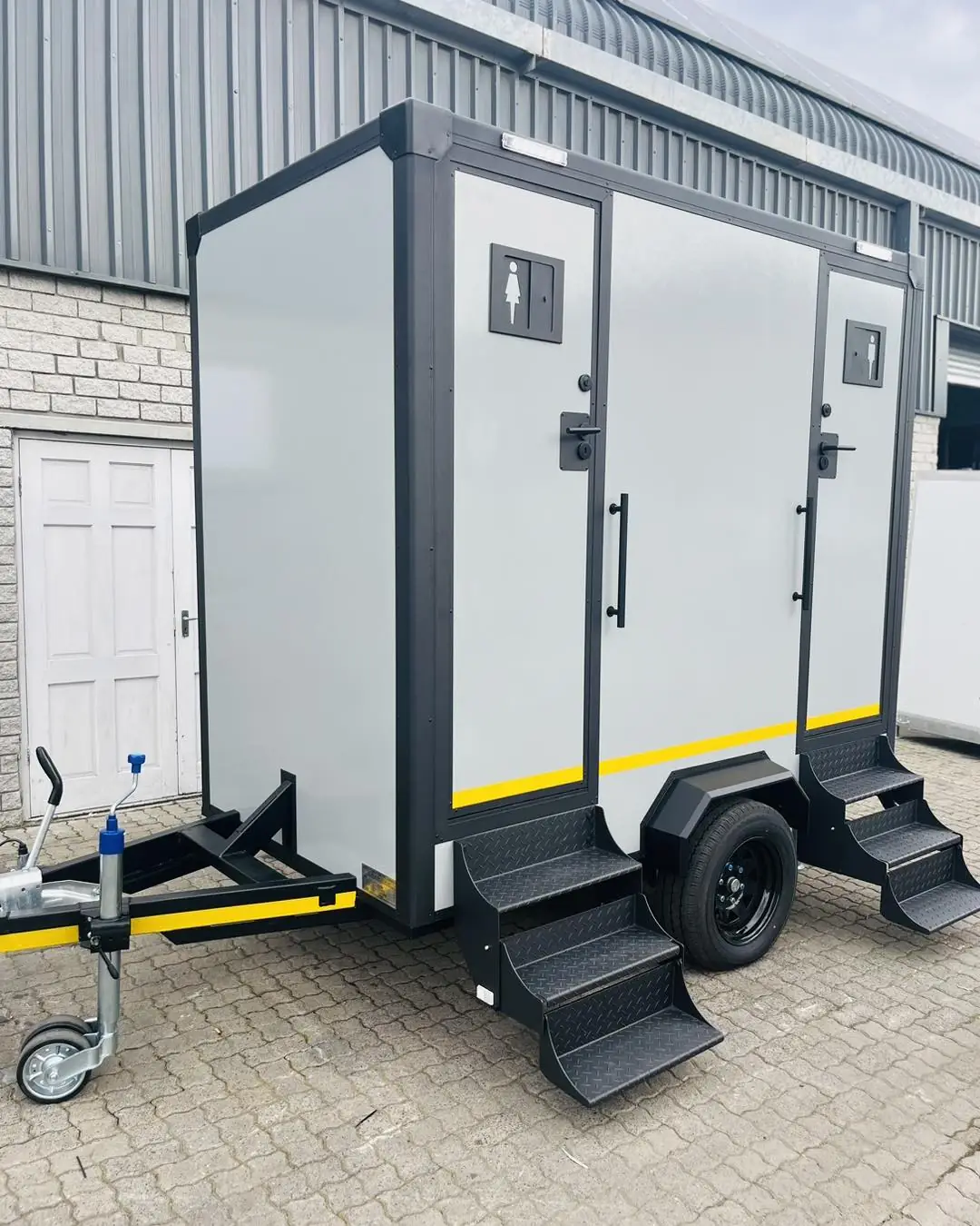 White two-stall restroom trailer with steps to each door